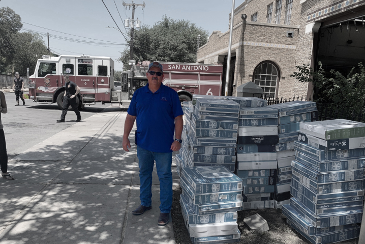 Man in blue shirt looking to camera in front of firehouse