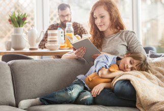 Child sleeping on mother's lap on couch while she read