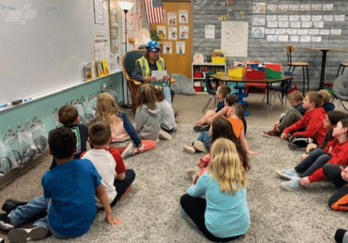 Image of Jill Sydik reading book to elementary schoolers