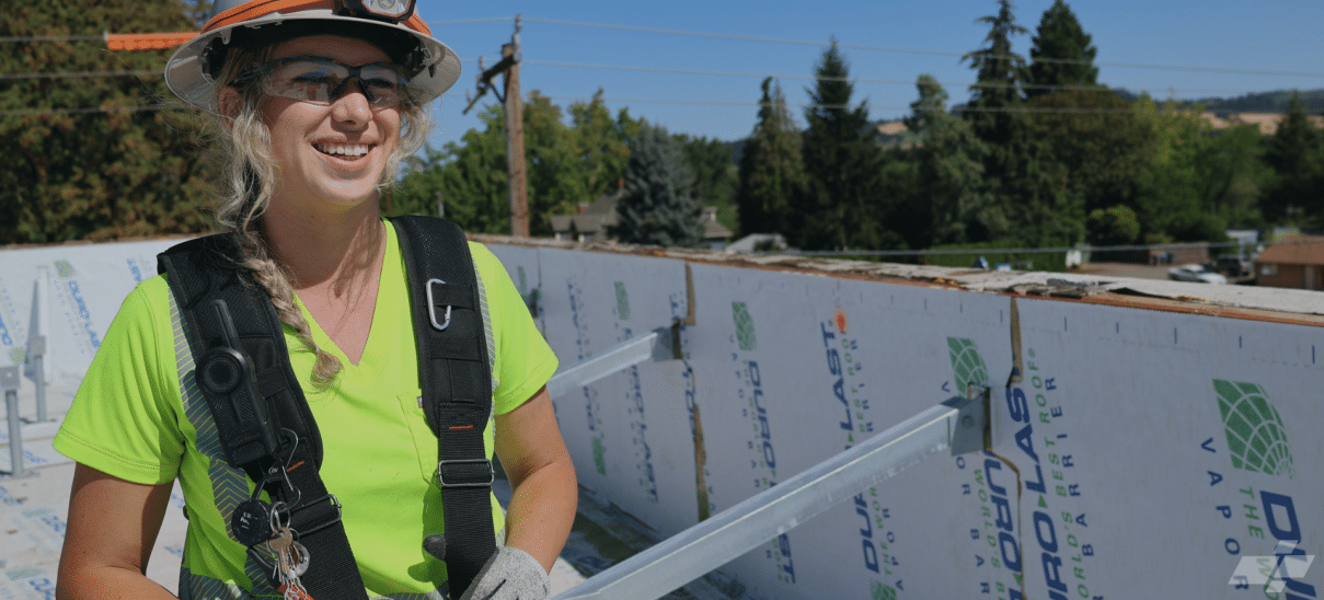 Woman in hardhat and green safety tshirt in front of steel beams