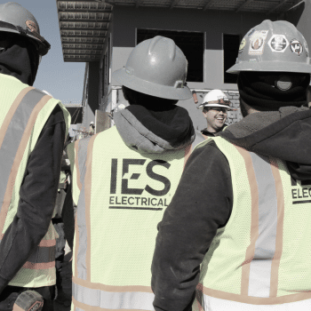 Image from behind of three IES employees talking to one IES employee with hardhat and headlamp