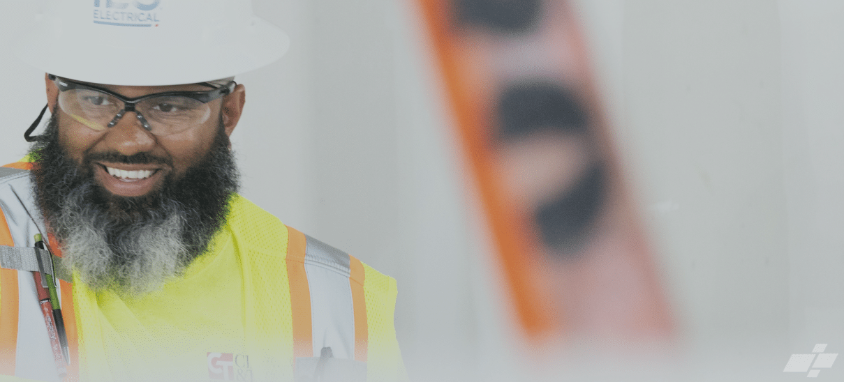 Man in hardhat and safety glasses and yellow safety vest smiling