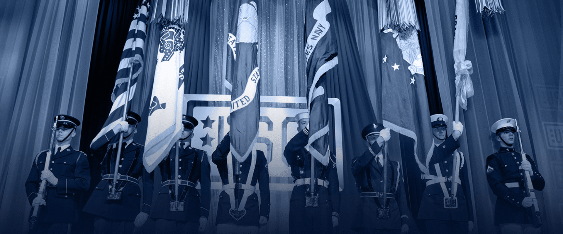 Blue overlay on image of eight military members holding flags