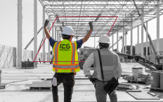 Black and white image of steel framing construction site with two IES employees - one in full color and safety gear