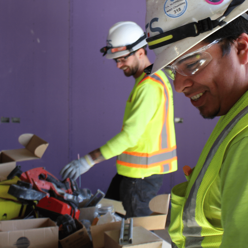 Two IES employees in safety green safety gear smiling