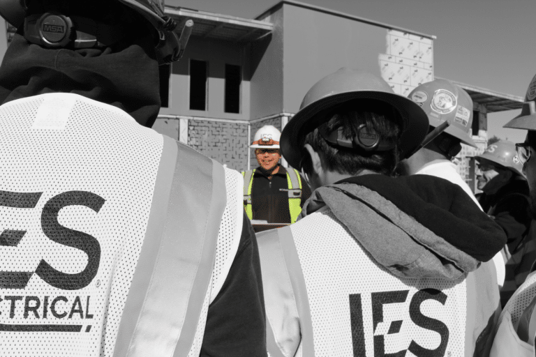 Black and white image from behind of IES employees listening to employee in full color