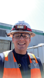 Cameron smiling into camera wearing white hardhat and safety glasses