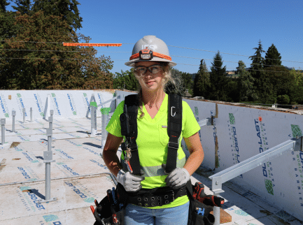 Hannah in safety gear and harness at jobsite